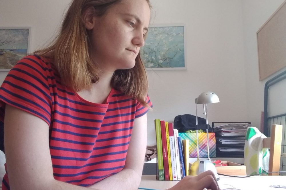 Julia sitzt mit Laptop am Schreibtisch und arbeitet